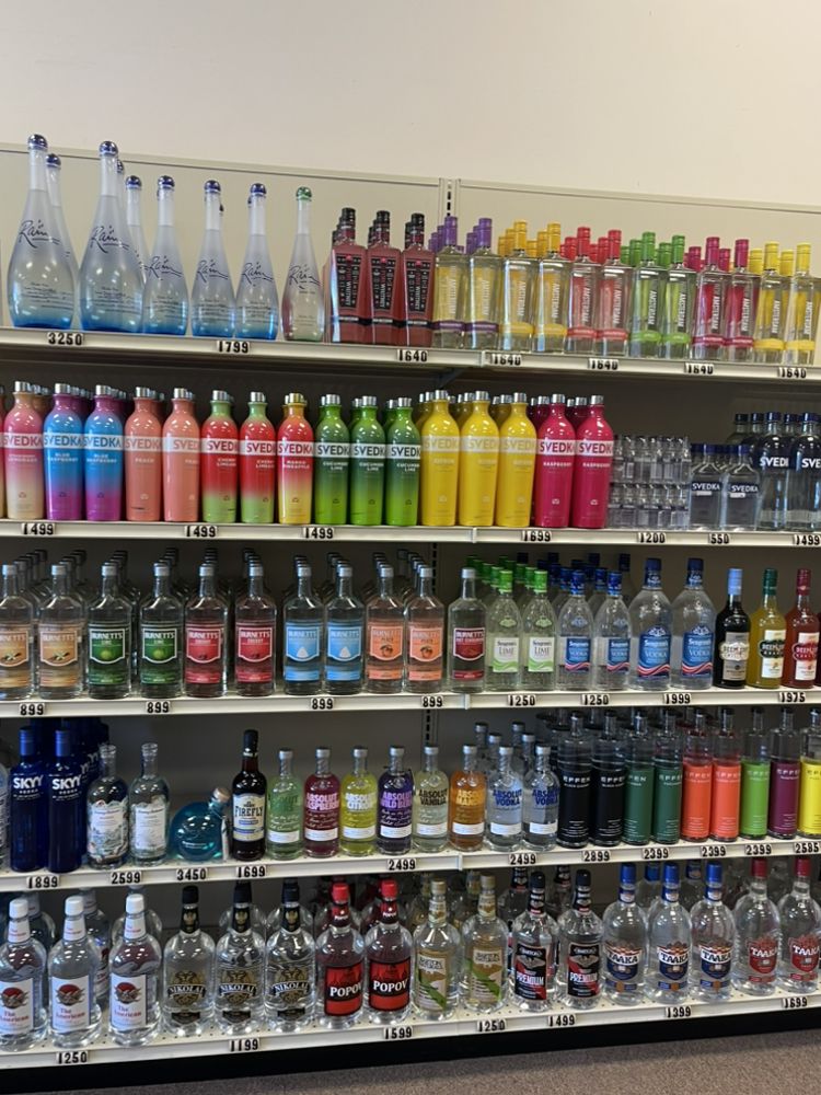 A variety of colorful liquor bottles neatly arranged on one of our shelves