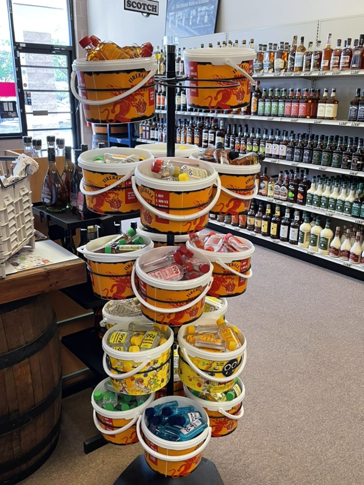 A store display of small assorted bottles of liquor in Fireball branded buckets