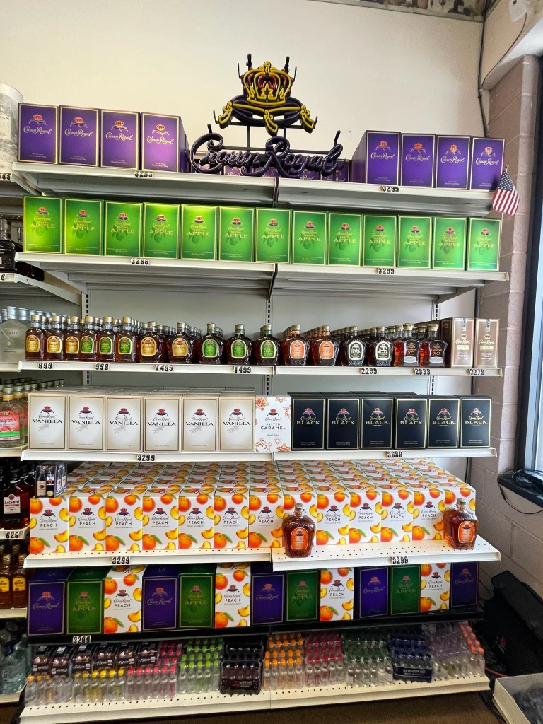 A neatly arranged display of Crown Royal whiskey with a neon sign at the top.