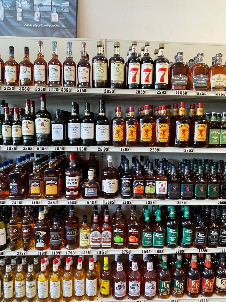 A shelf containing whiskey and bourbon brands like Jameson, Jim Beam, Fireball, & Evan Williams.