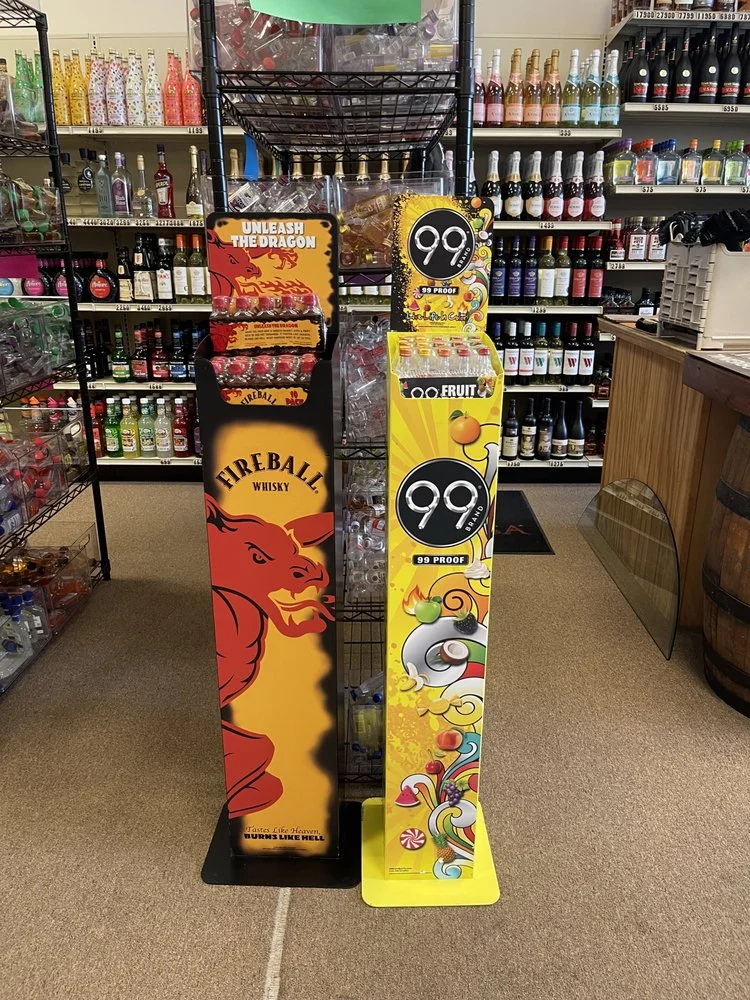 A vibrant store display of Fireball whiskey and 99 Brand fruit flavored alcohol beverages.