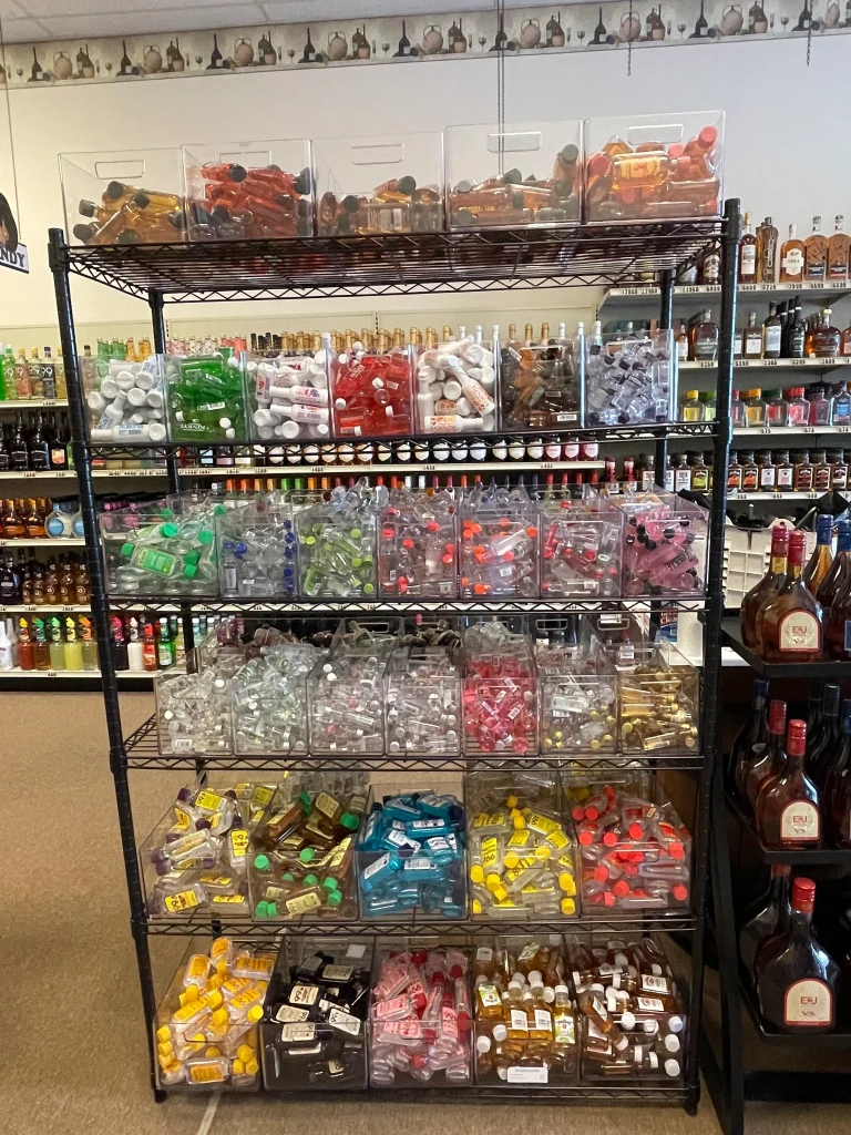 A rack full of small liquor bottles in our store separated neatly in clear bins.